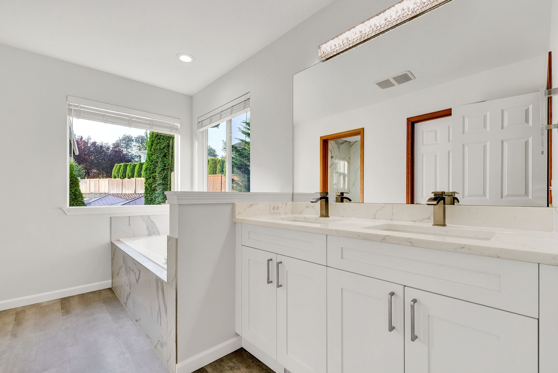 A bathroom with two sinks , a tub and a window.