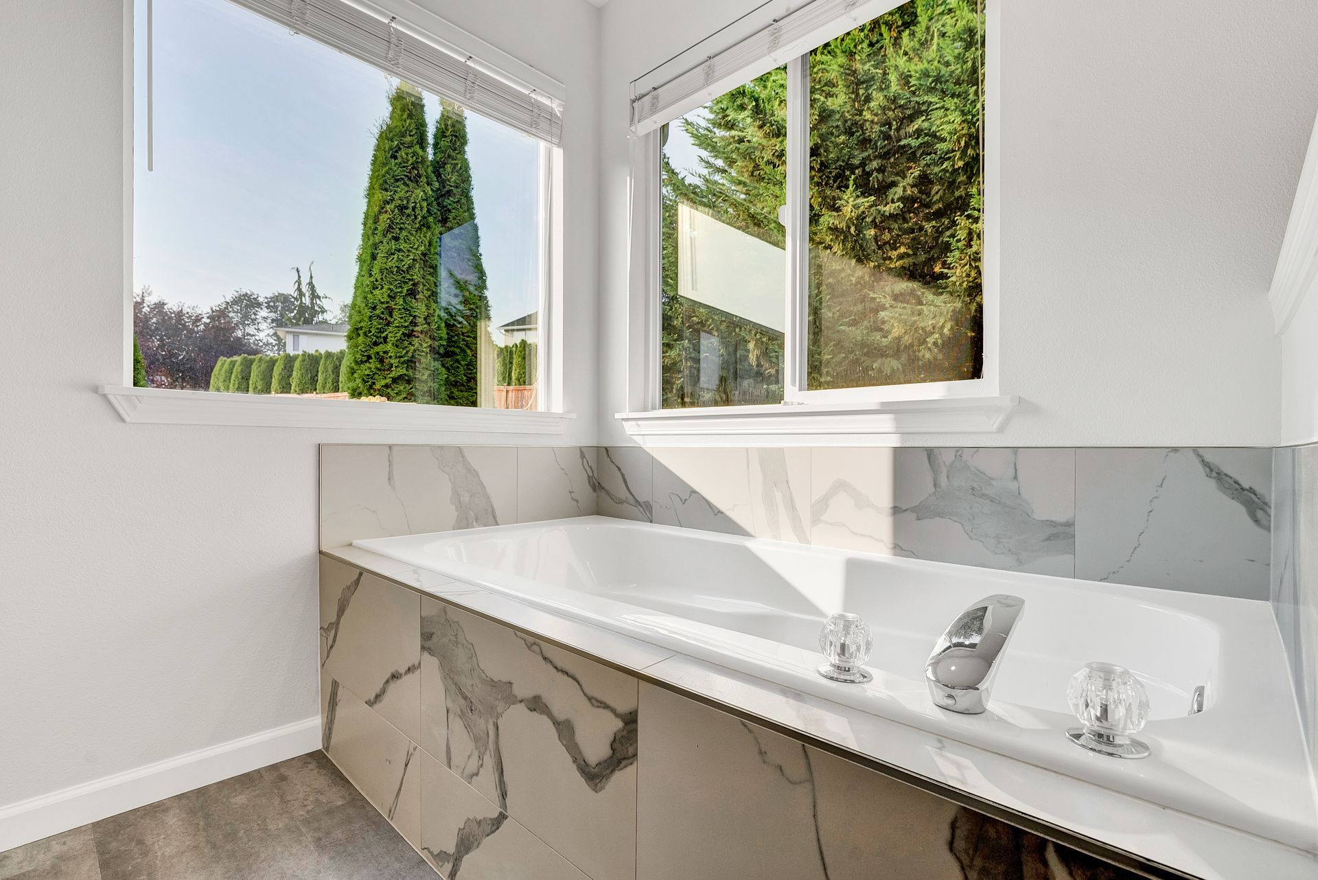 A bathroom with a bathtub and a window with trees in the background.