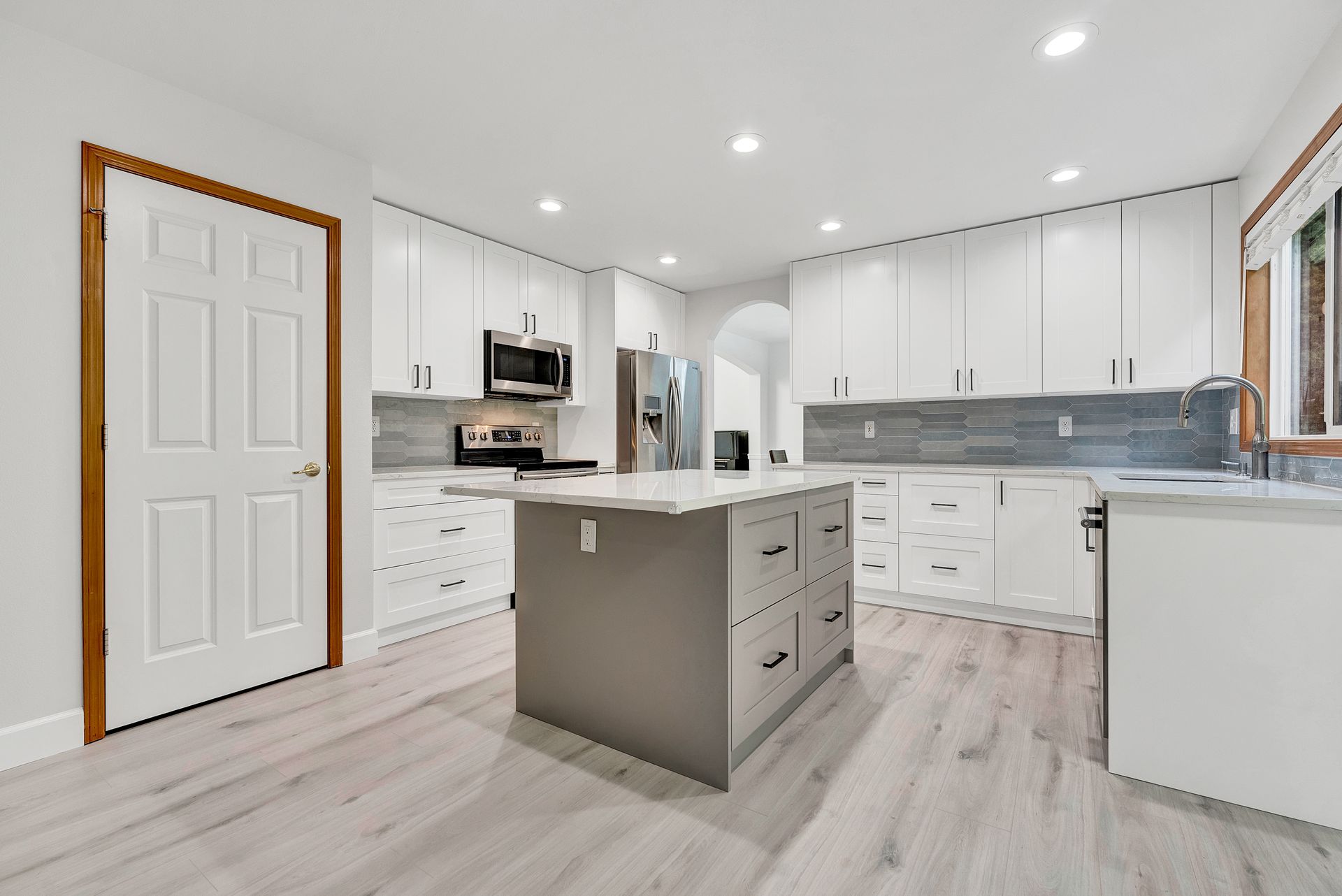 A kitchen with white cabinets and a large island in the middle.