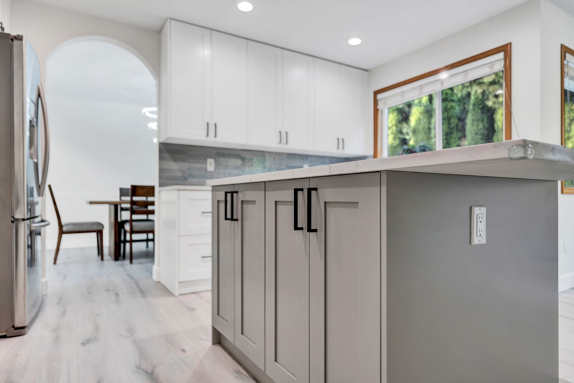 A kitchen with white cabinets and a large island in the middle.