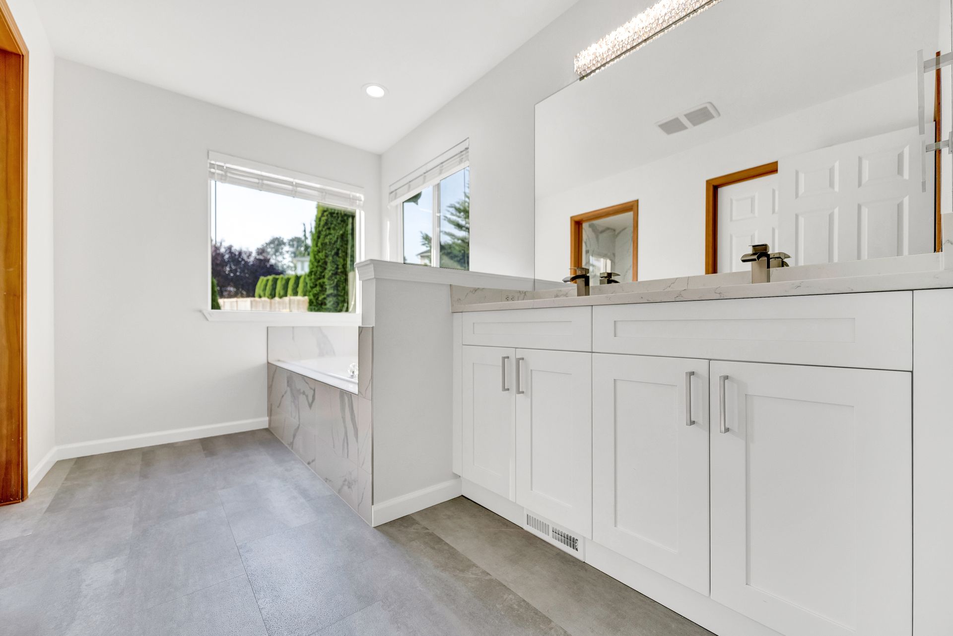 A bathroom with two sinks , a tub and a window.