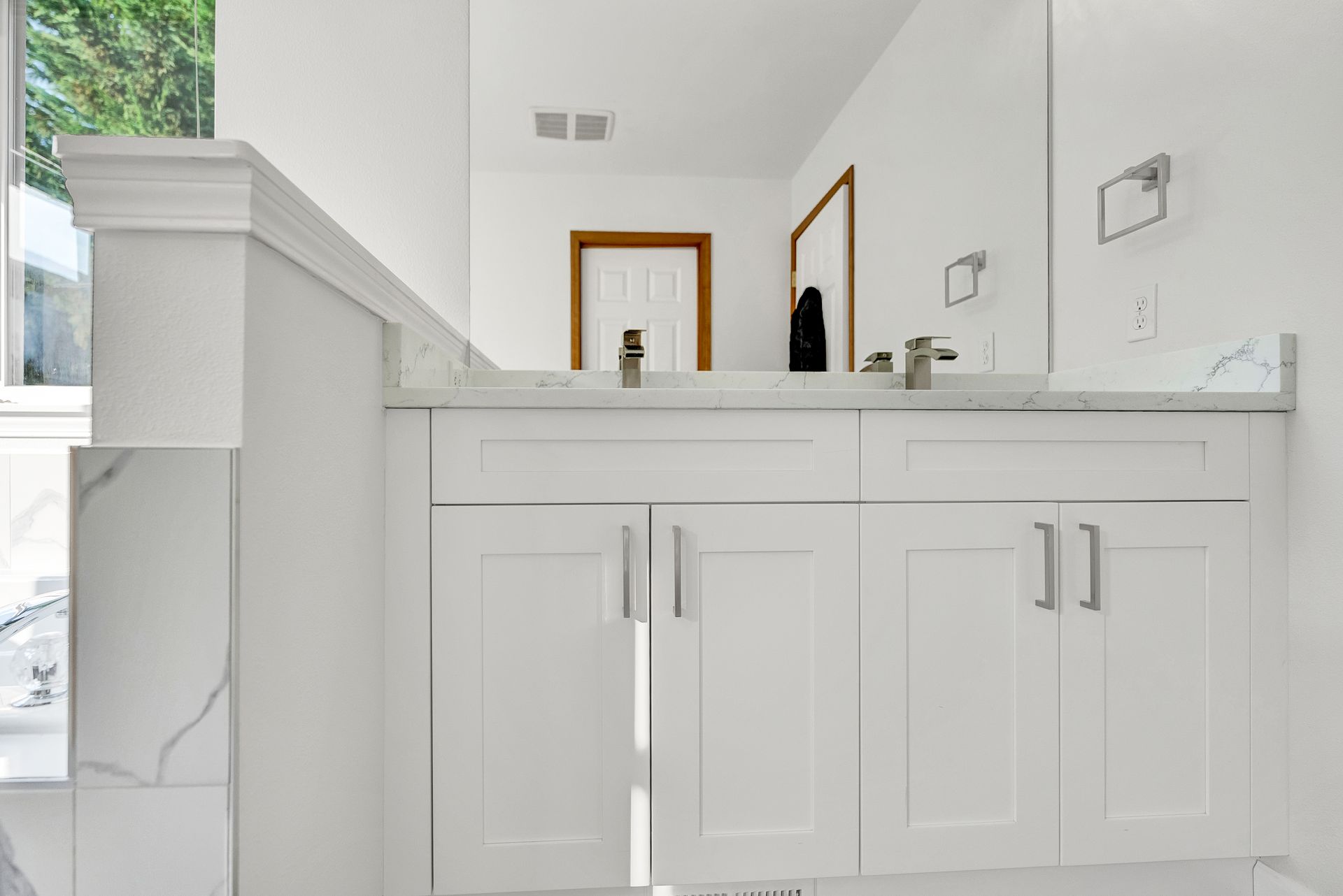 A bathroom with white cabinets and a large mirror.