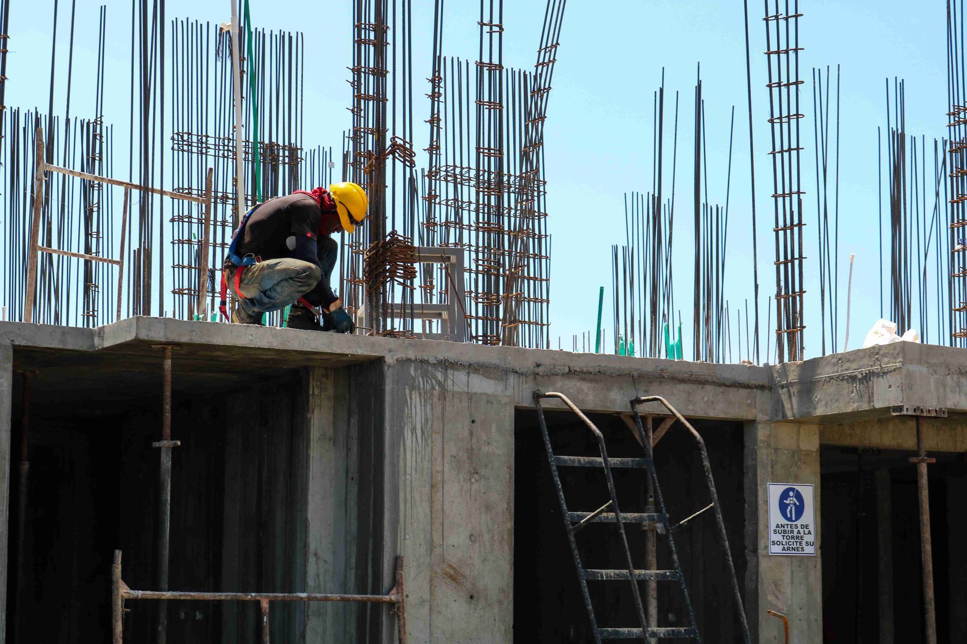 A construction worker is working on the roof of a building under construction.