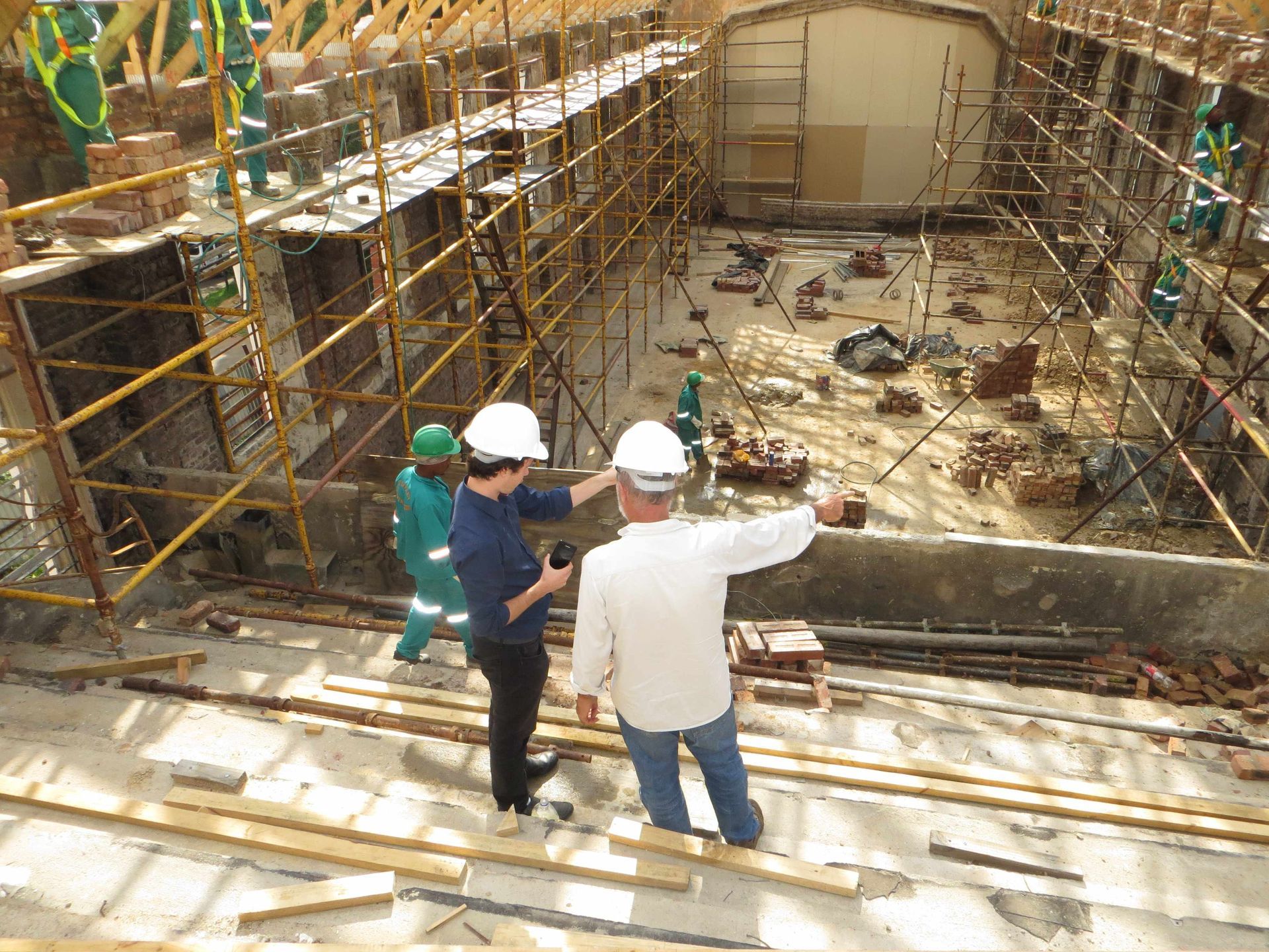 Two men are standing in front of a building under construction.