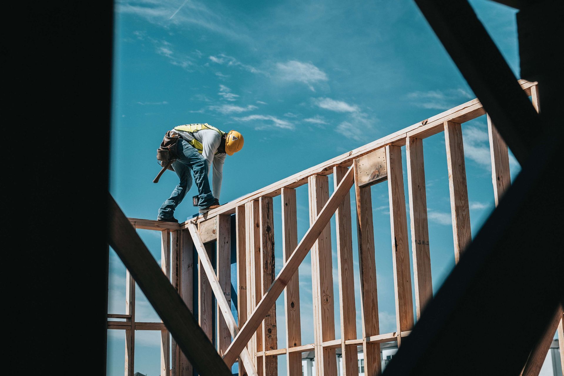 A construction worker is standing on top of a wooden structure.