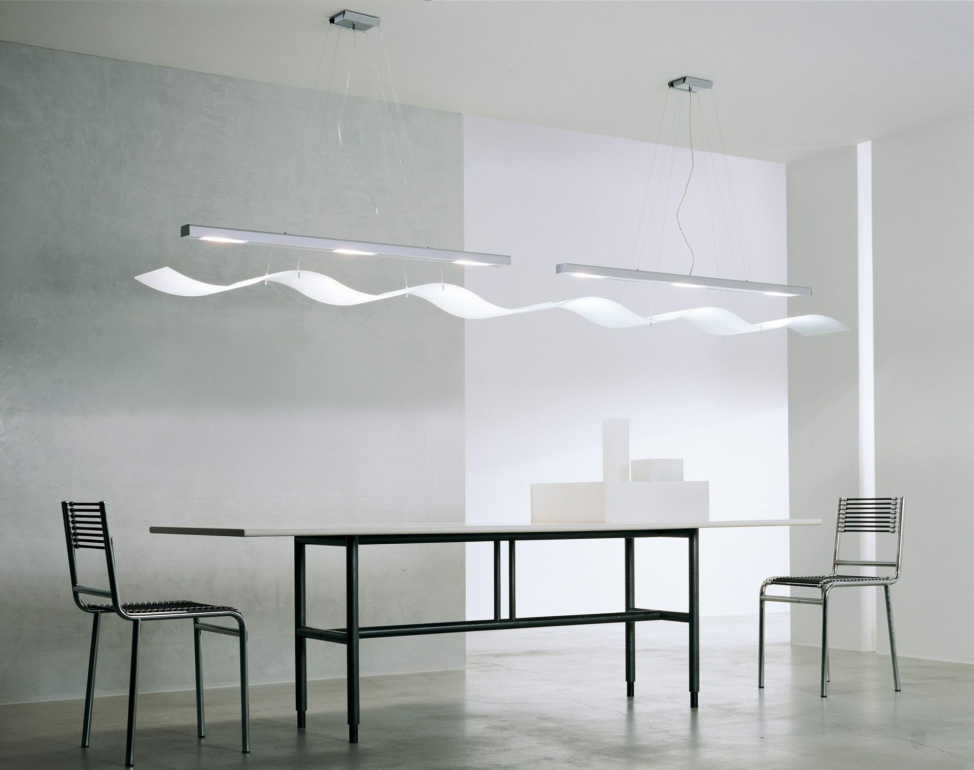A table and chairs in a room with a light hanging from the ceiling