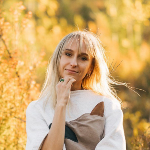 A woman in a white sweater is holding a cat pillow.