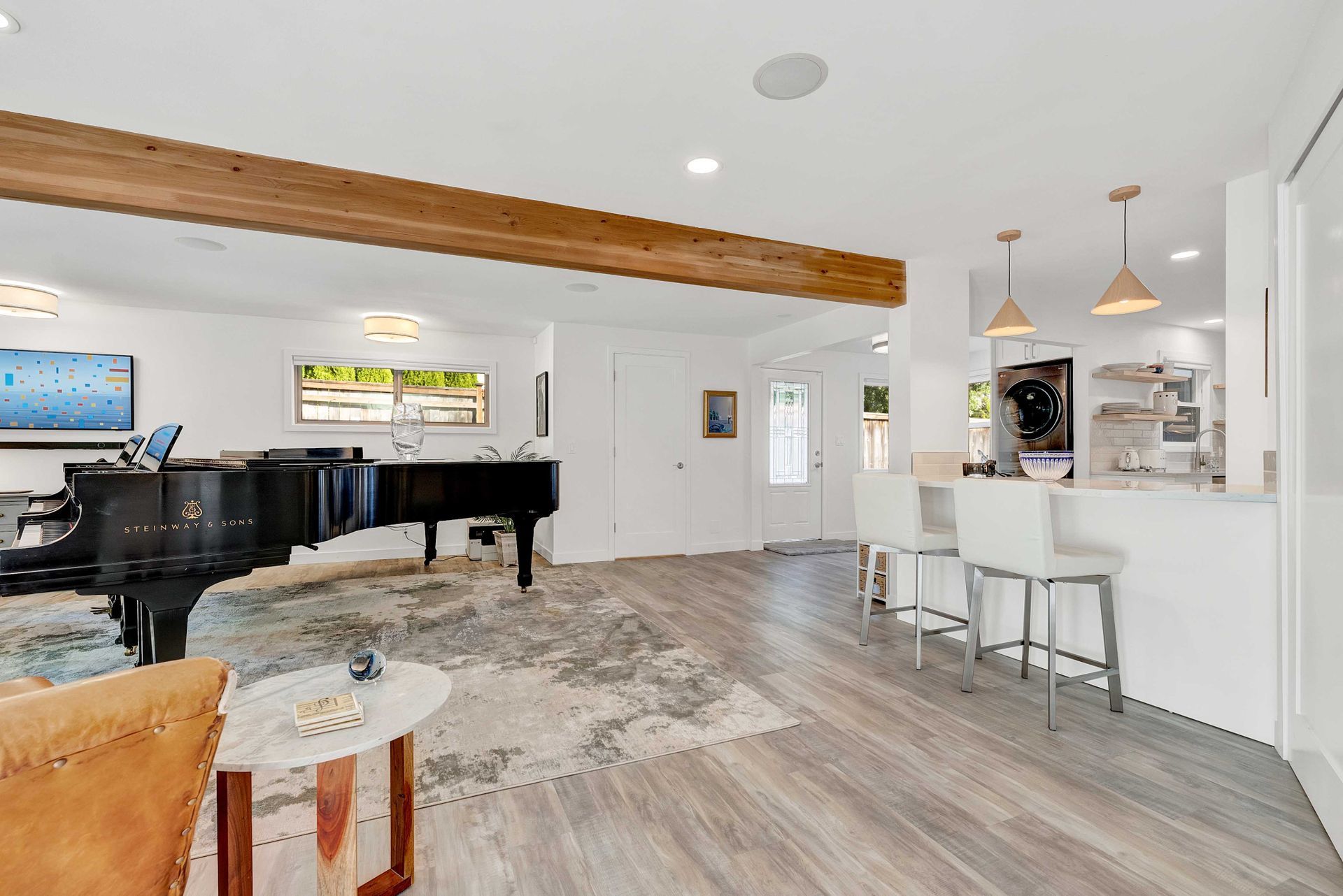 A living room with a piano , chairs , and a table.