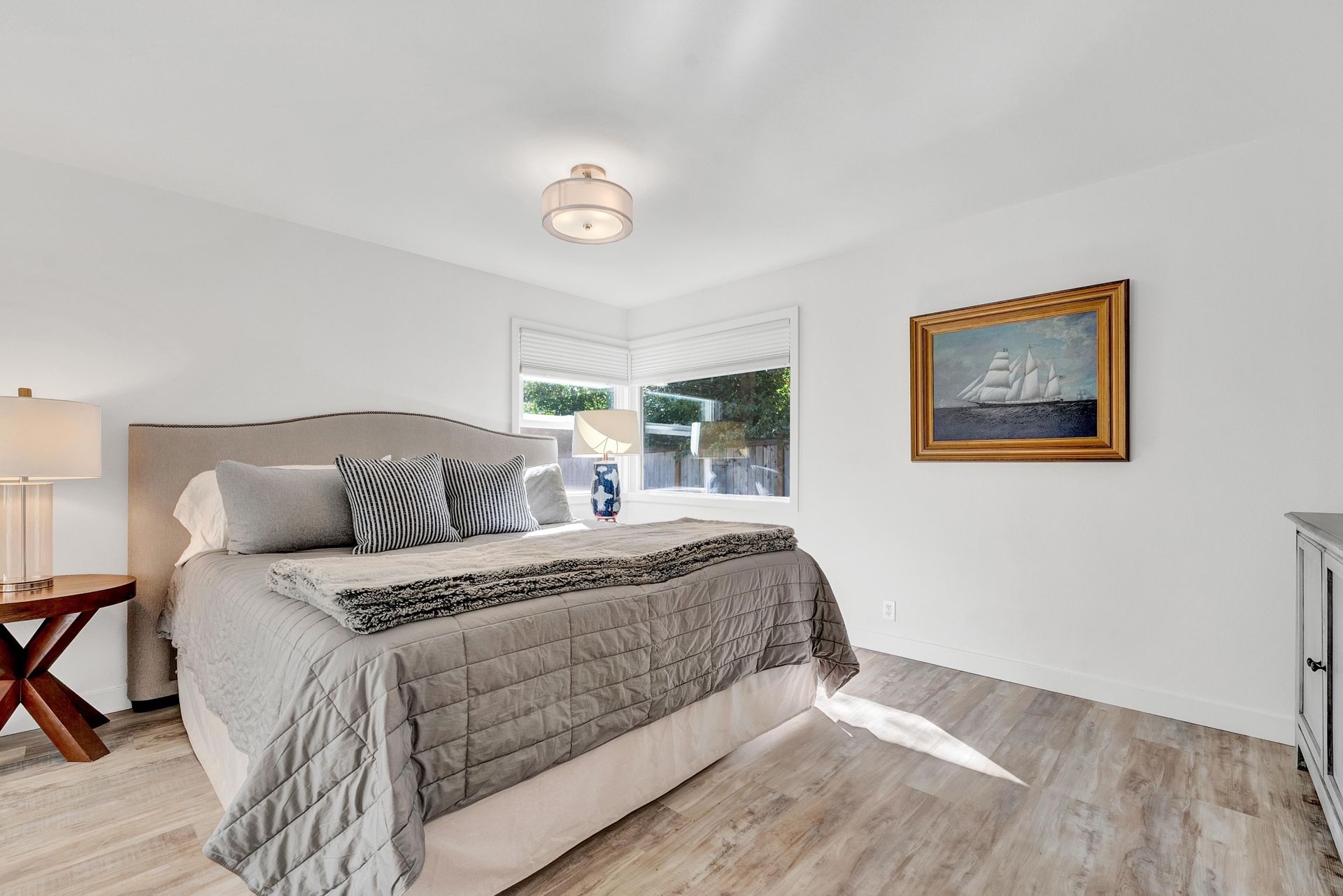 A bedroom with a large bed and a painting on the wall.