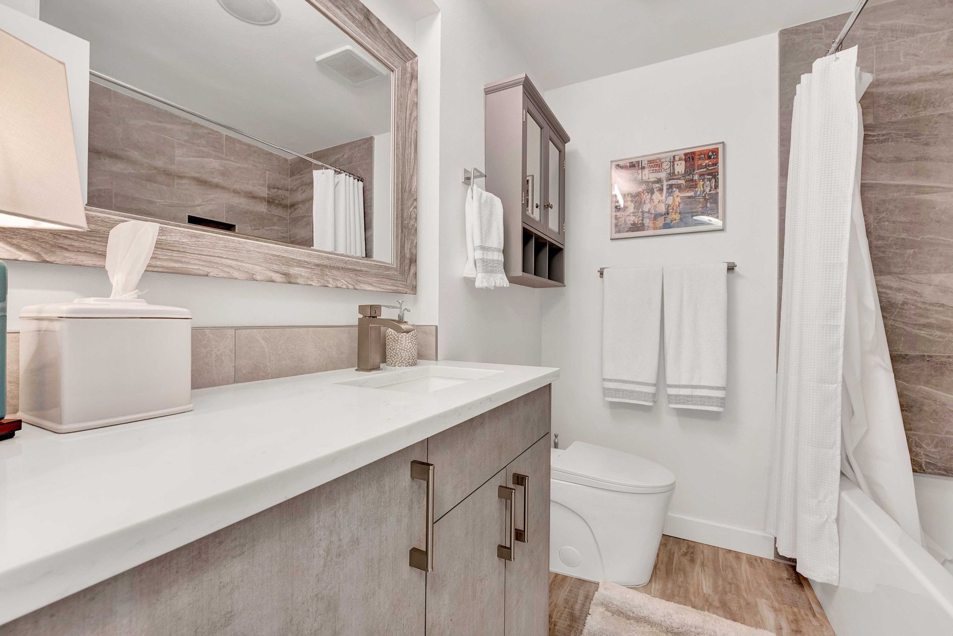 A bathroom with a sink , toilet , shower and mirror.