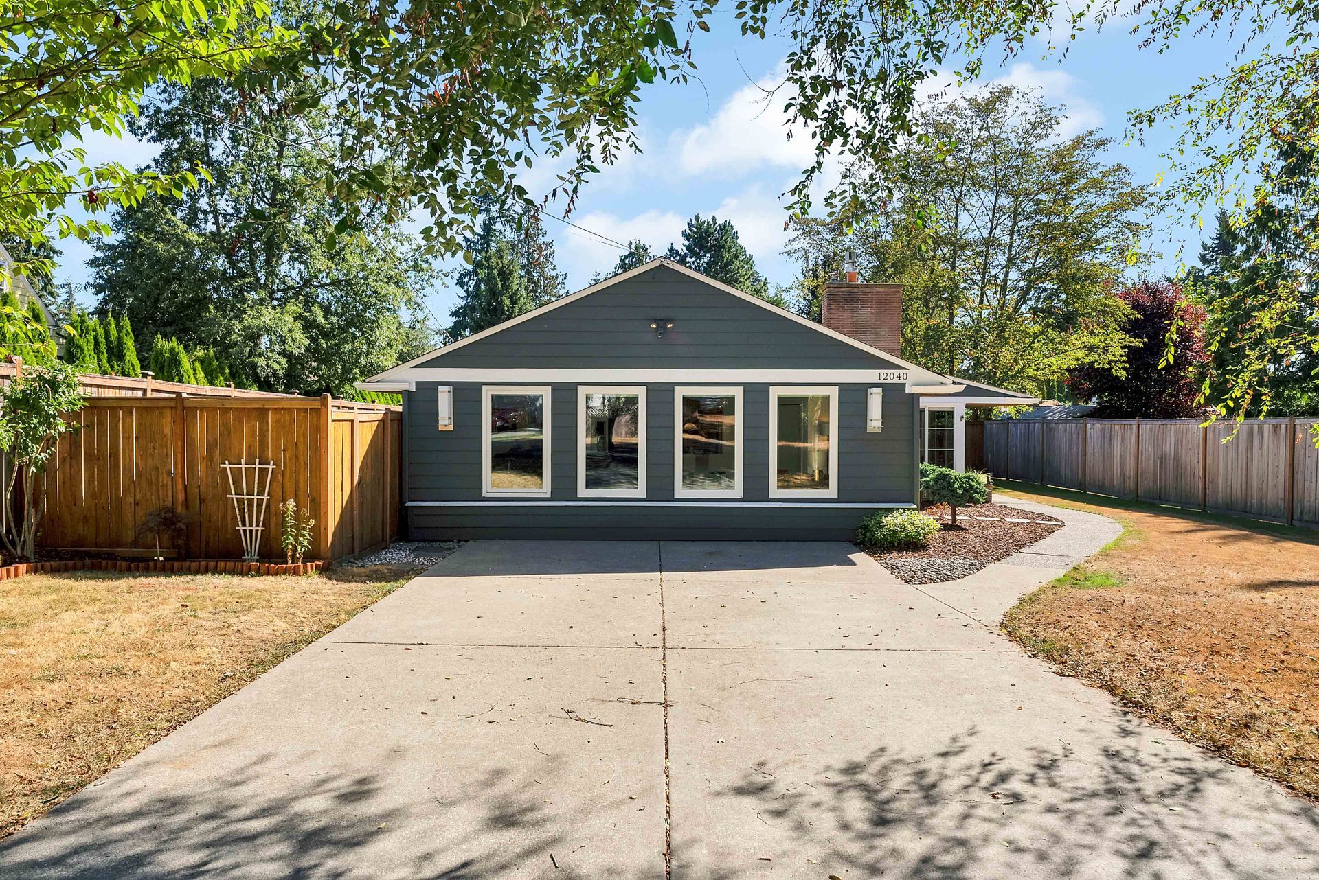 A house with a driveway and a fence in front of it