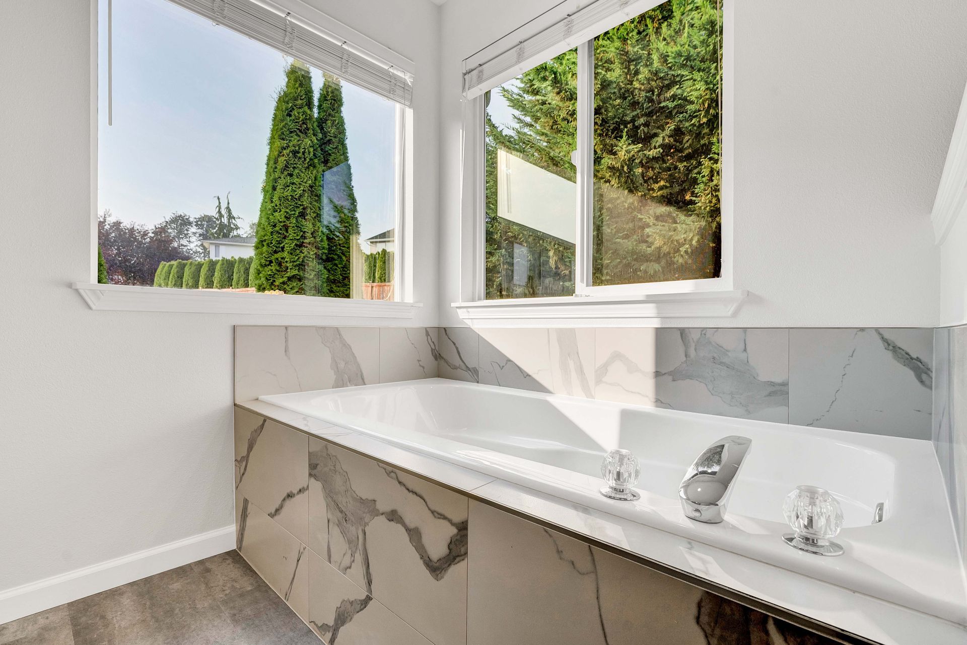 A bathroom with a bathtub and a window with trees in the background.