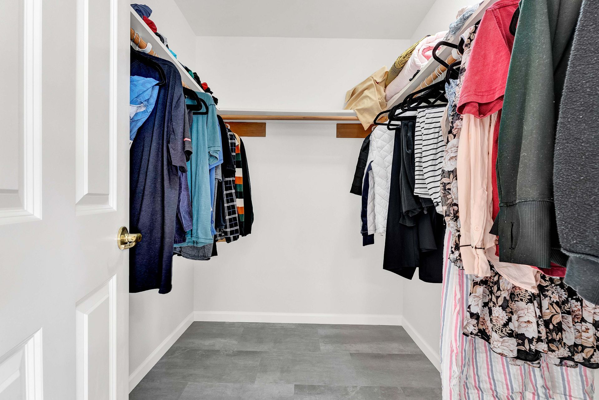 A walk in closet filled with lots of clothes hanging on racks.