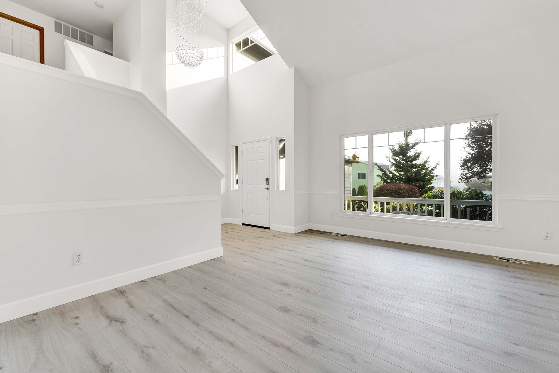 An empty living room with hardwood floors and white walls.