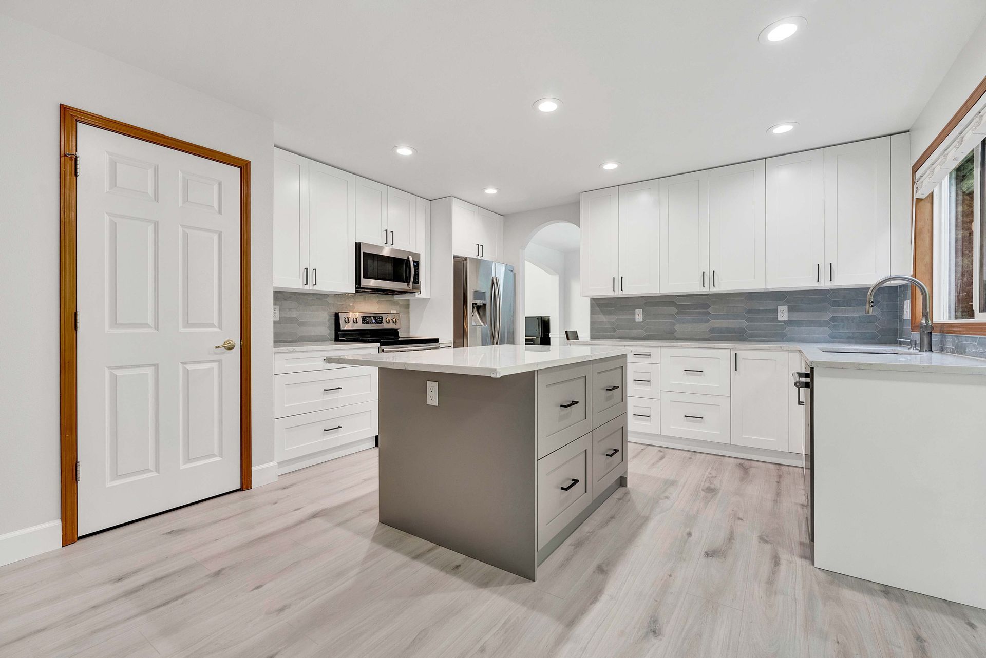 A kitchen with white cabinets and a large island in the middle.