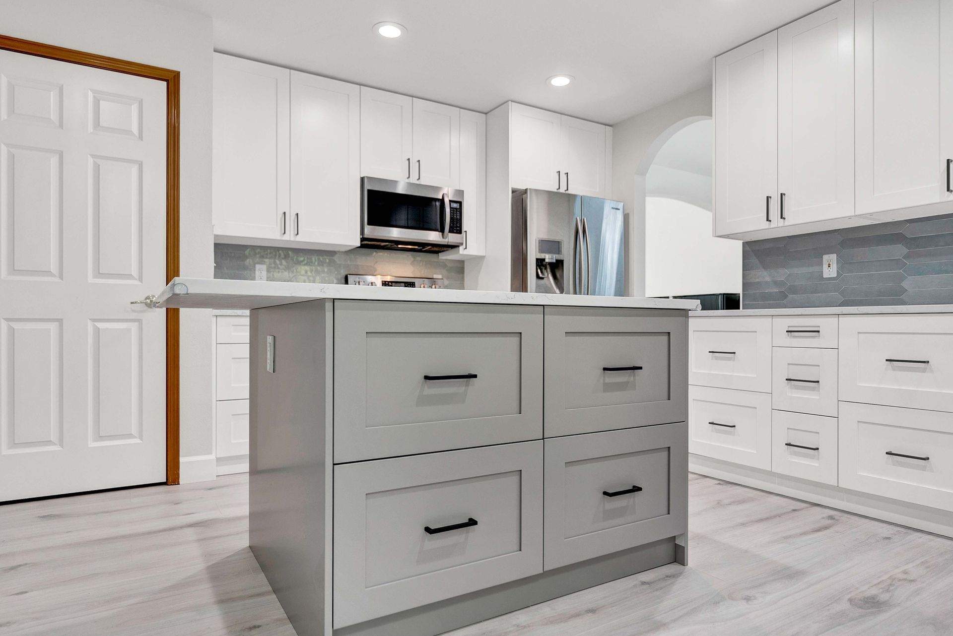 A kitchen with white cabinets and a large island in the middle.