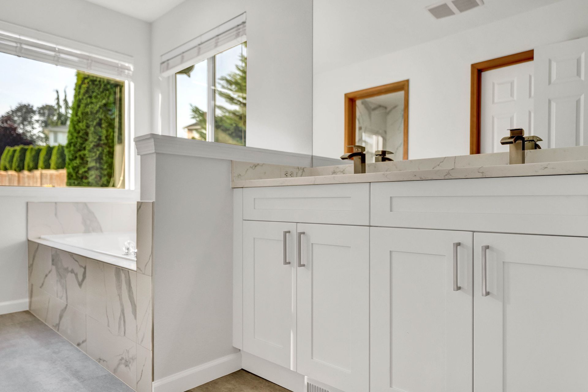 A bathroom with two sinks , a tub and a window.