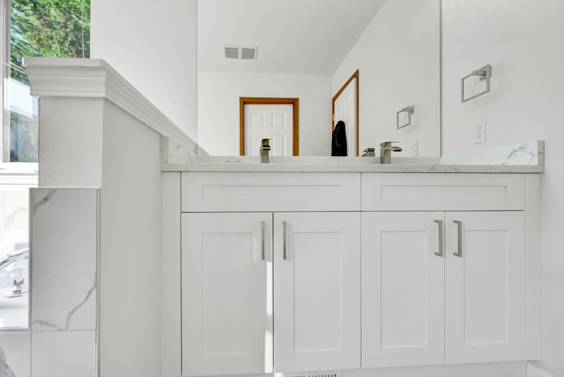 A bathroom with white cabinets and a large mirror.
