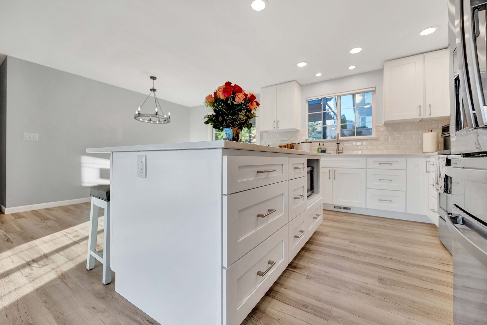 A kitchen with white cabinets and stainless steel appliances and a large island.