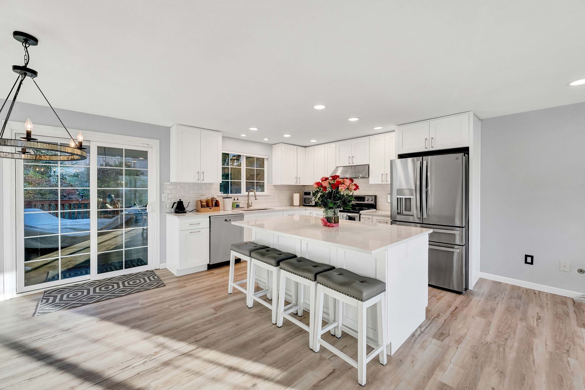 A kitchen with white cabinets , stainless steel appliances and a large island.