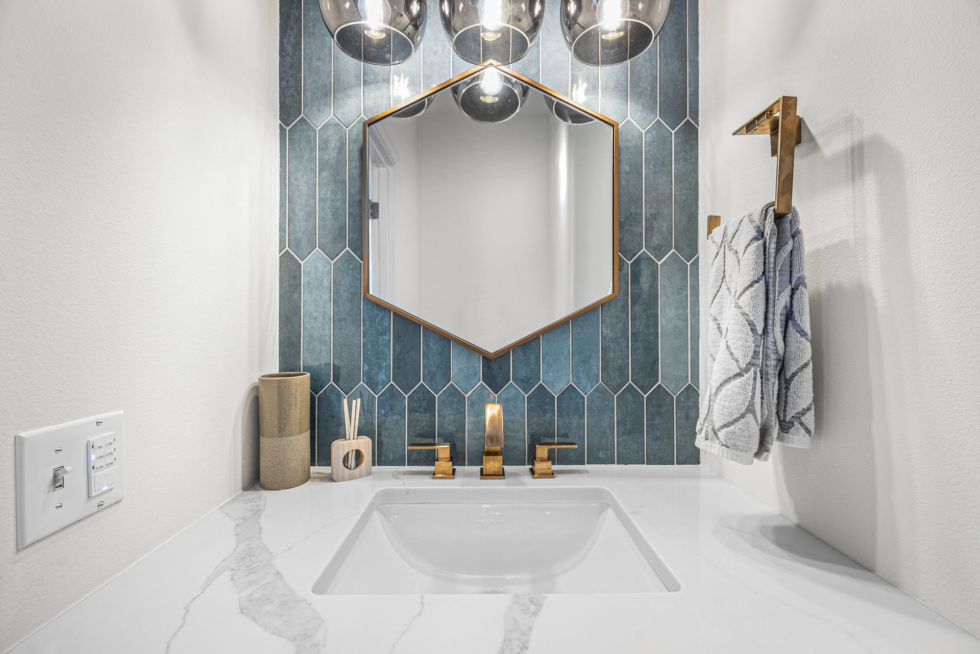 A bathroom with a sink , mirror and blue tiles.