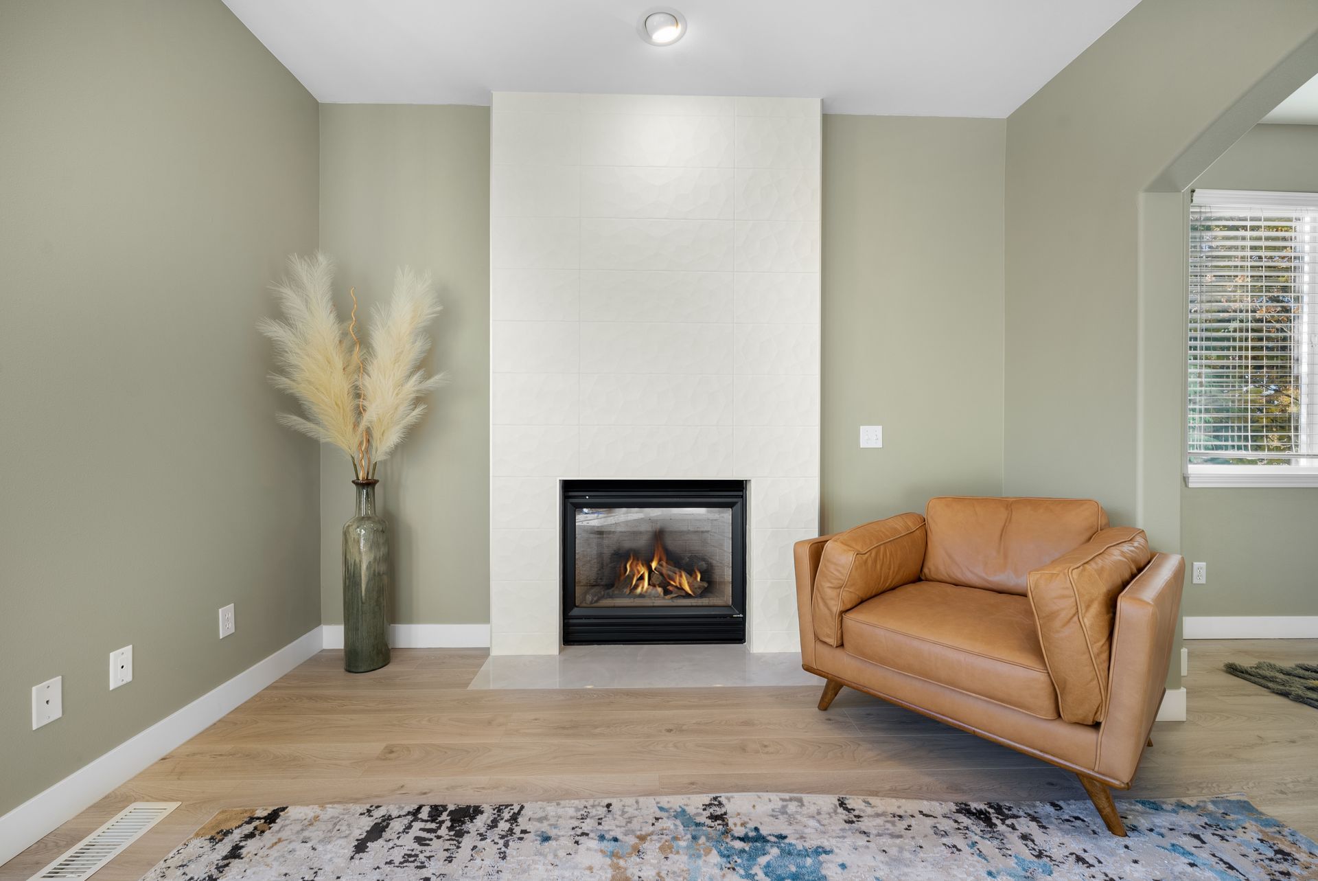 A living room with a fireplace , chair and rug.