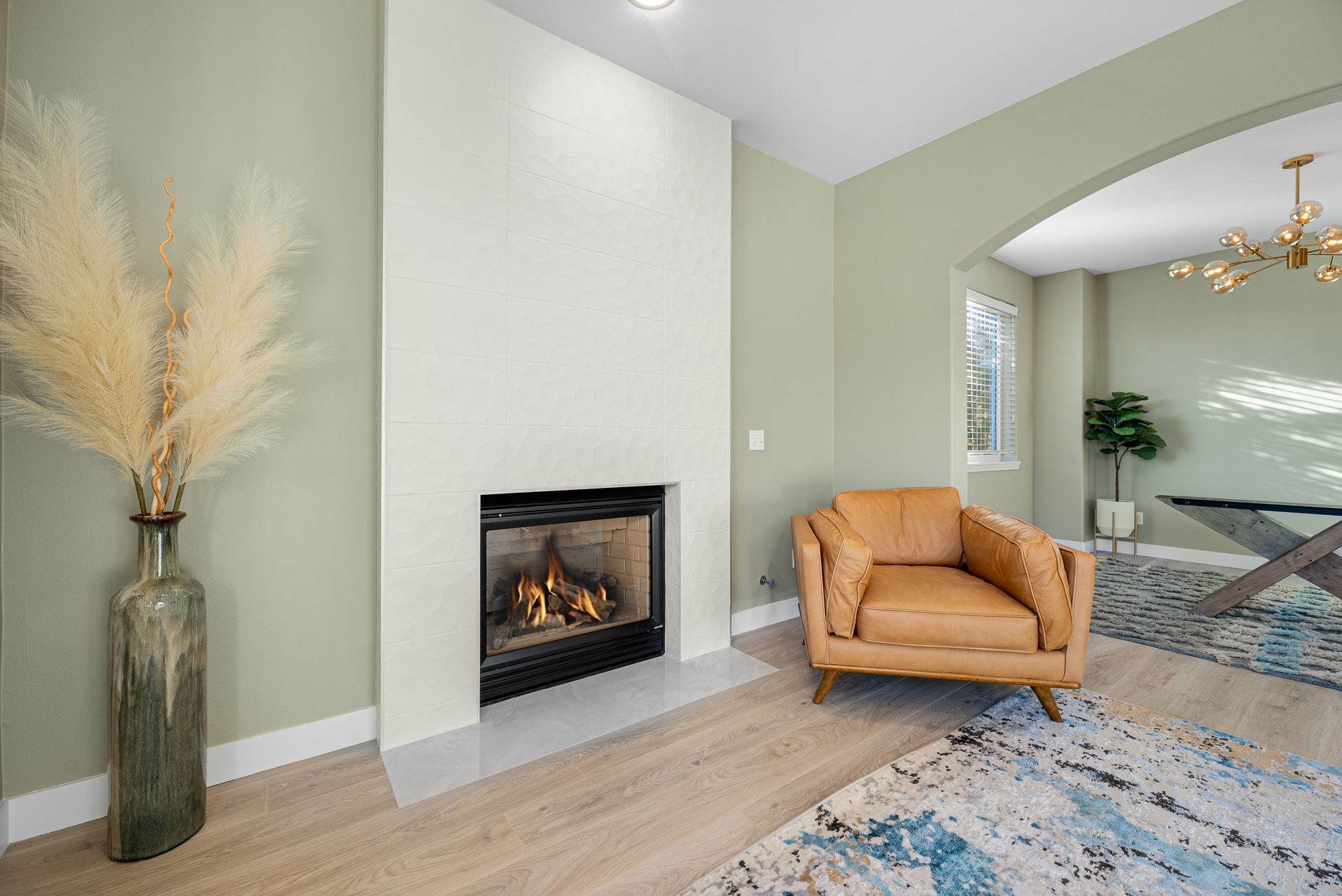 A living room with a fireplace , chair , vase and rug.