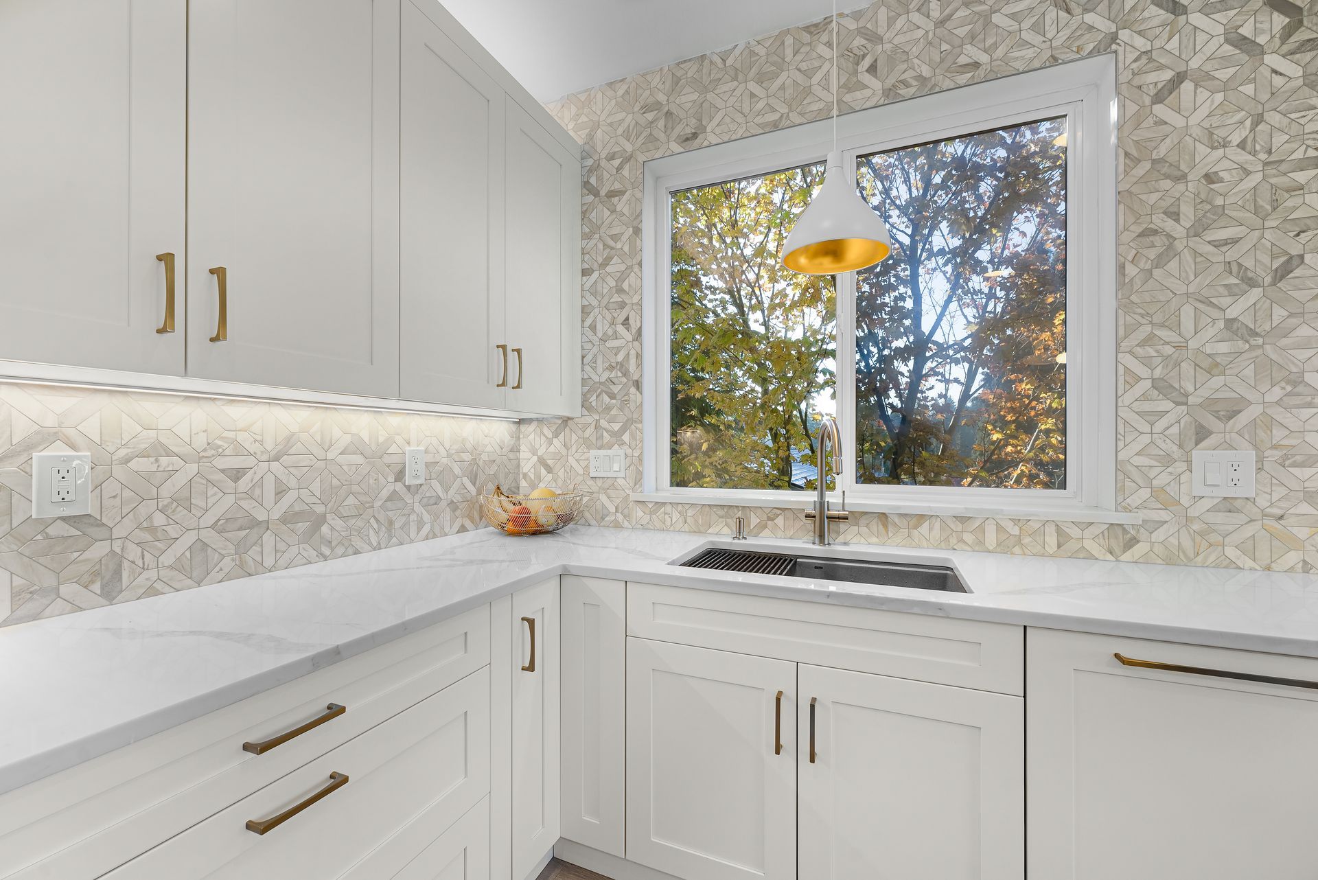 A kitchen with white cabinets , a sink , and a window.