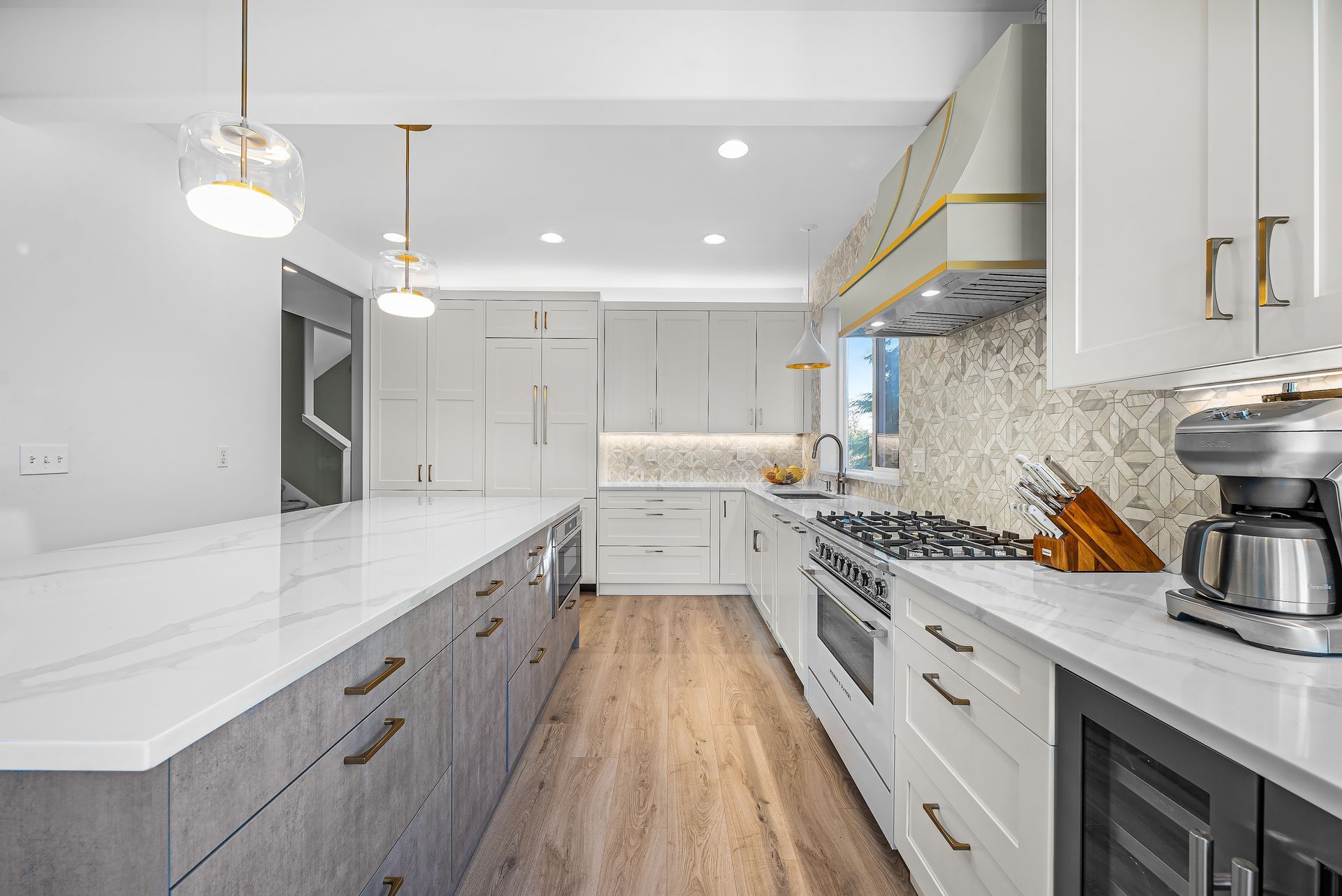 A kitchen with white cabinets , granite counter tops , stainless steel appliances and a coffee maker.