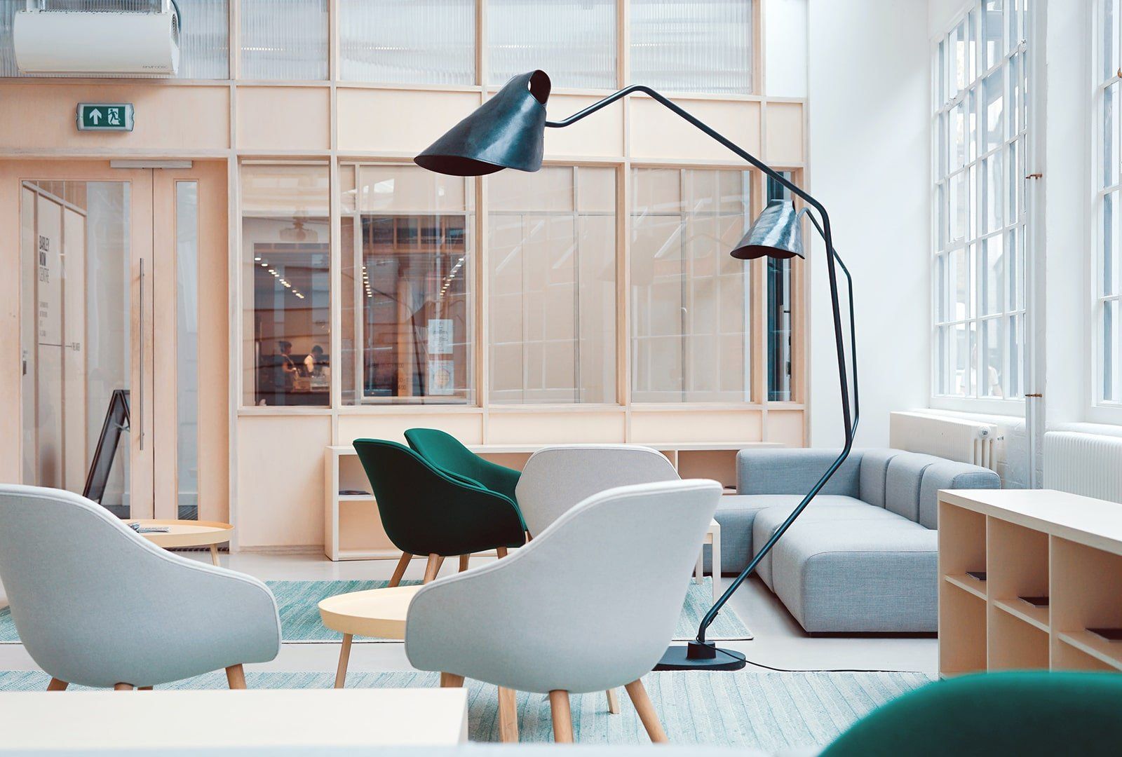 Elegant commercial building interior A living room with a couch , chairs , tables and a lamp.