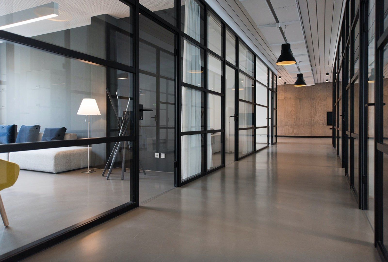 Modern commercial building interior A long hallway in a modern office building with glass walls.