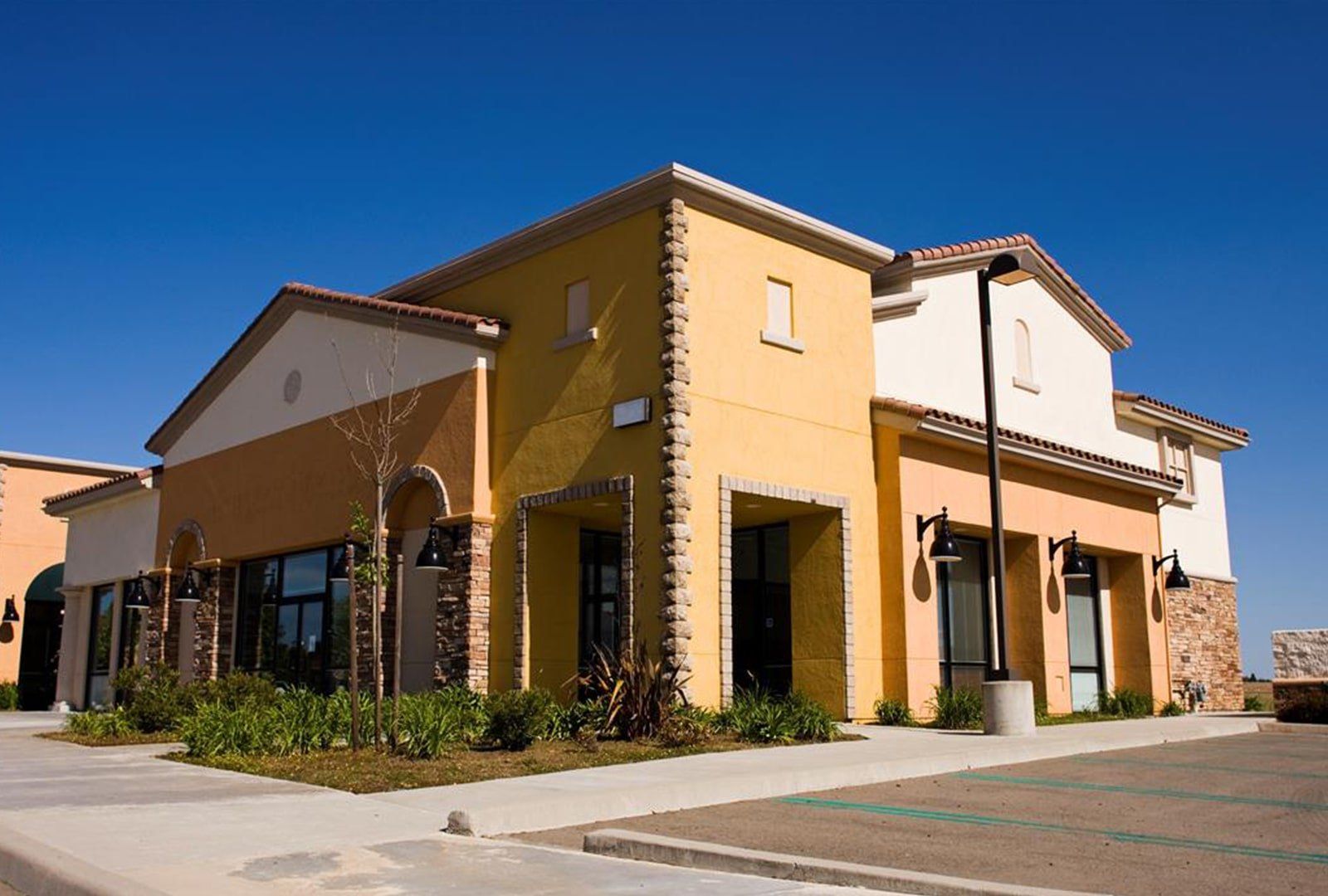 Stucco styled structure A yellow and white building with a parking lot in front of it