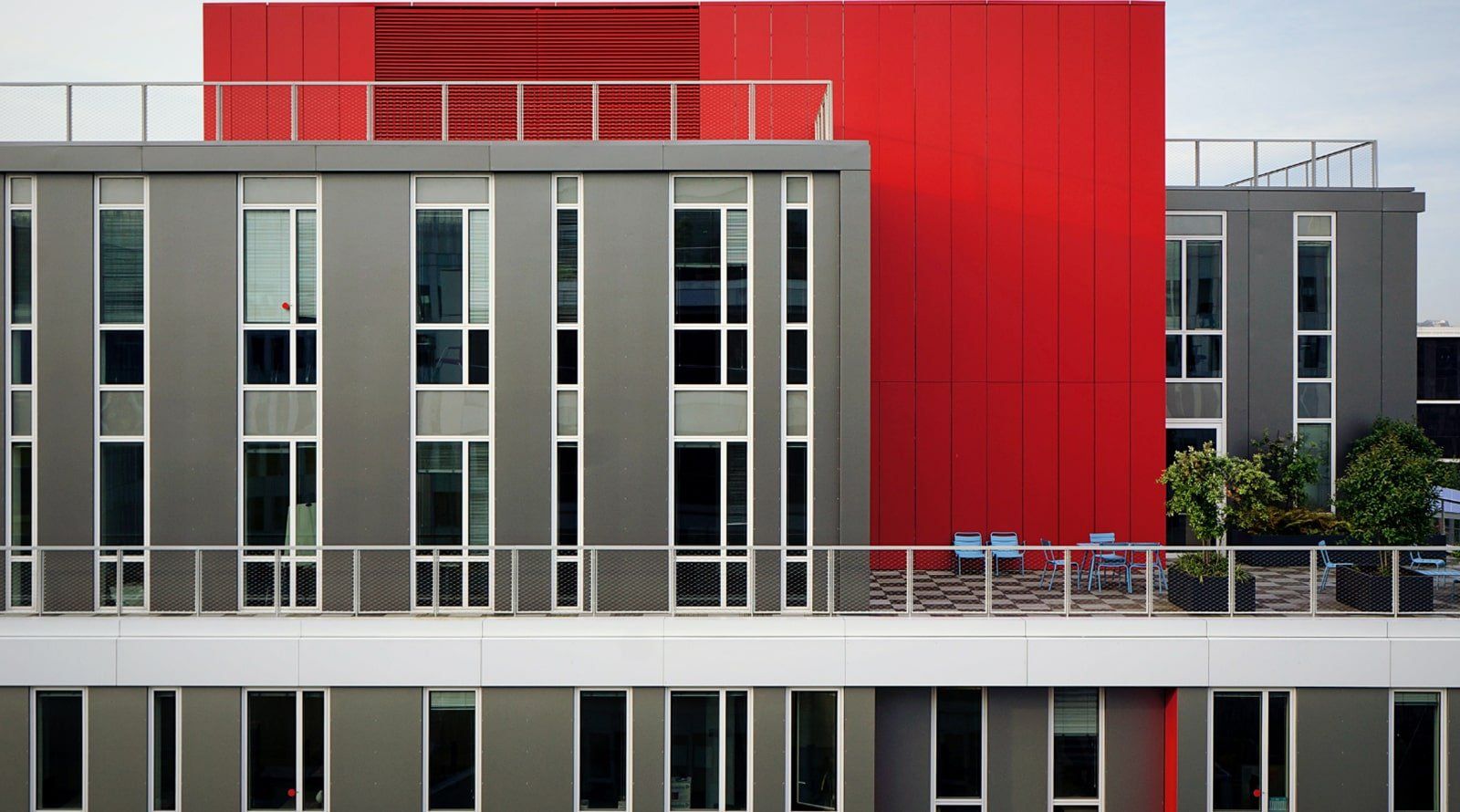Building made of concrete A red building with a balcony on top of it