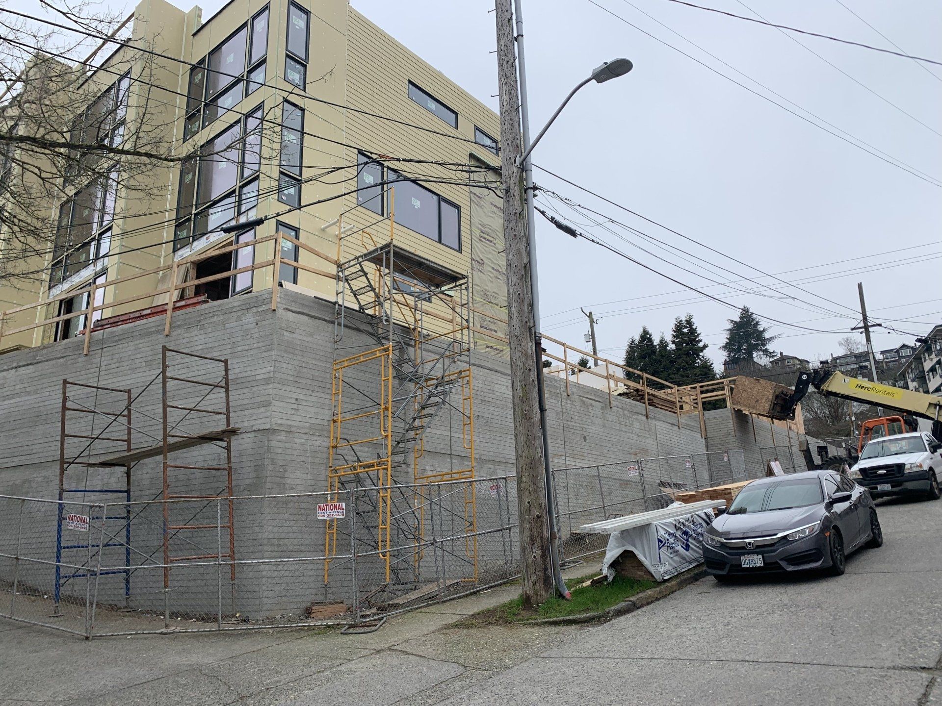 A car is parked in front of a building under construction.