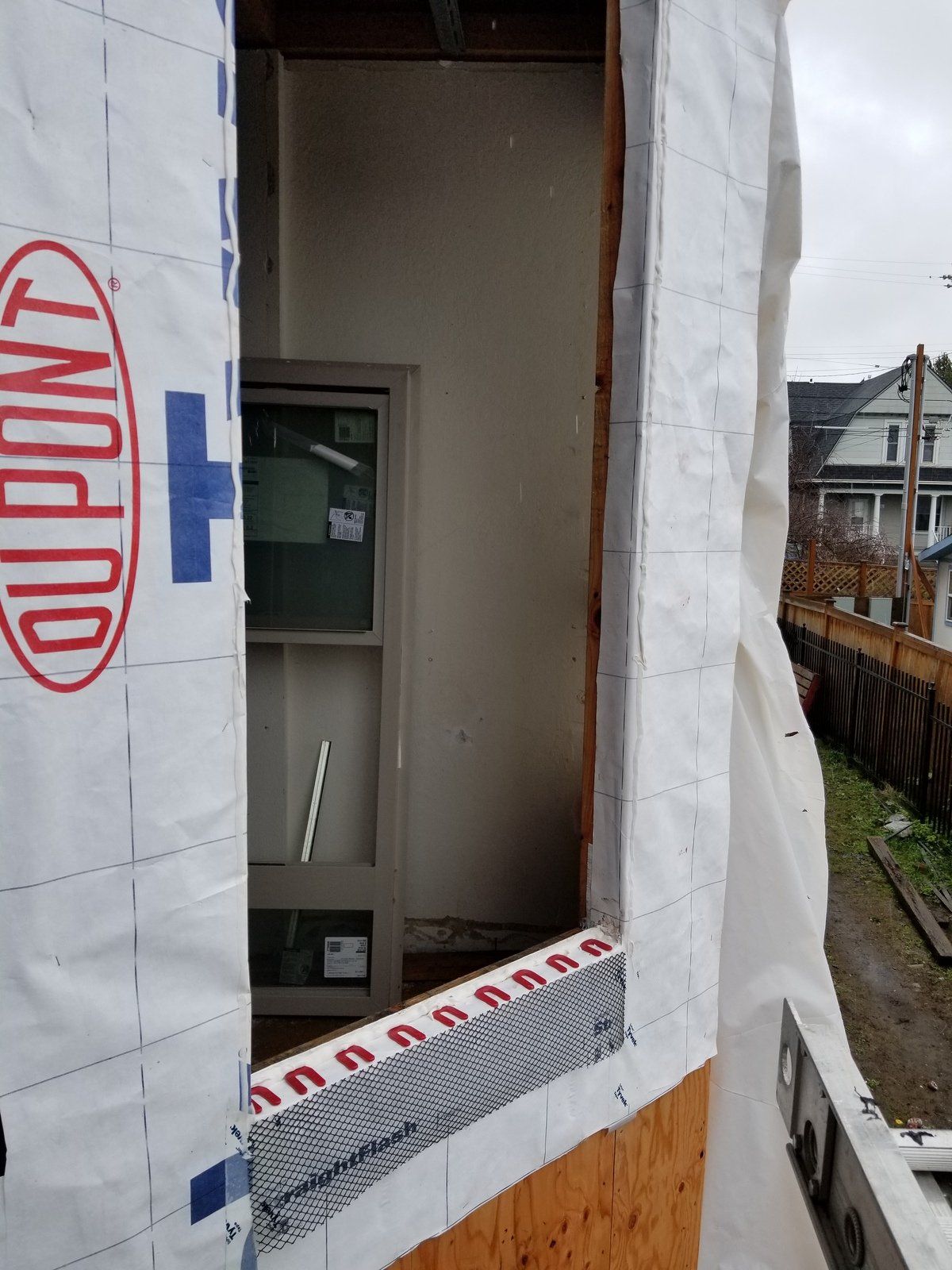 A window is being installed in a house with a dupont sheet covering it