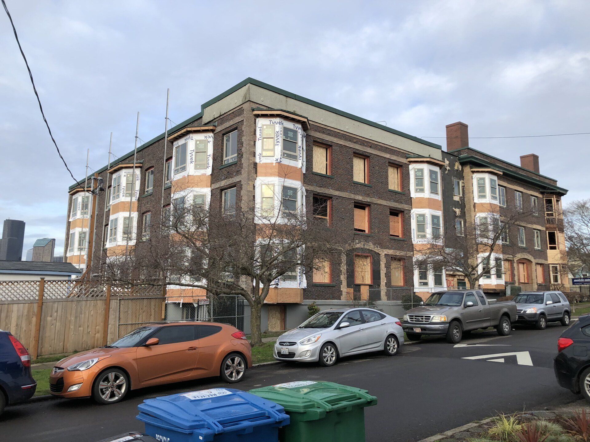 A row of cars are parked in front of a large building.