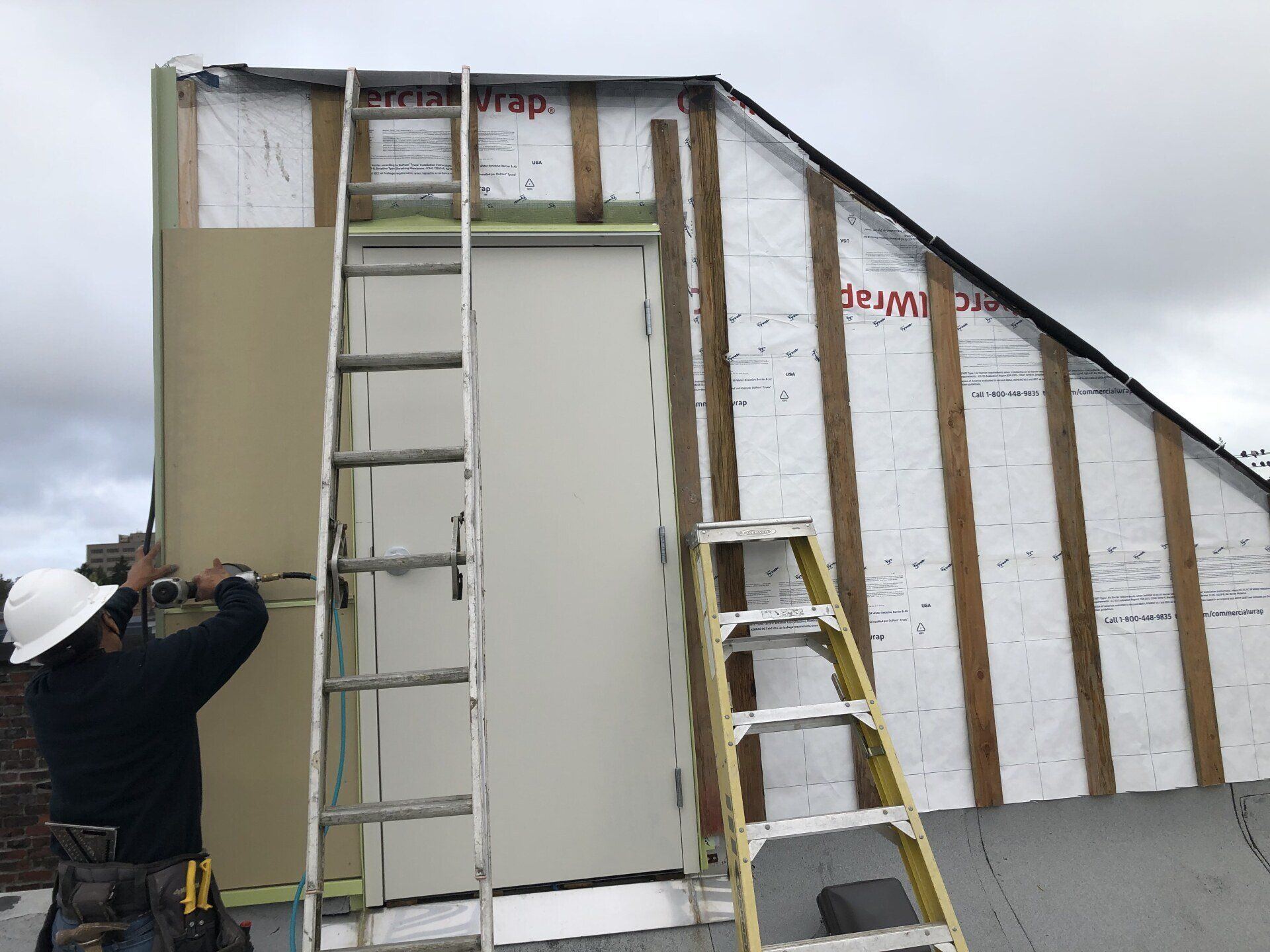 A man on a ladder is working on a wall