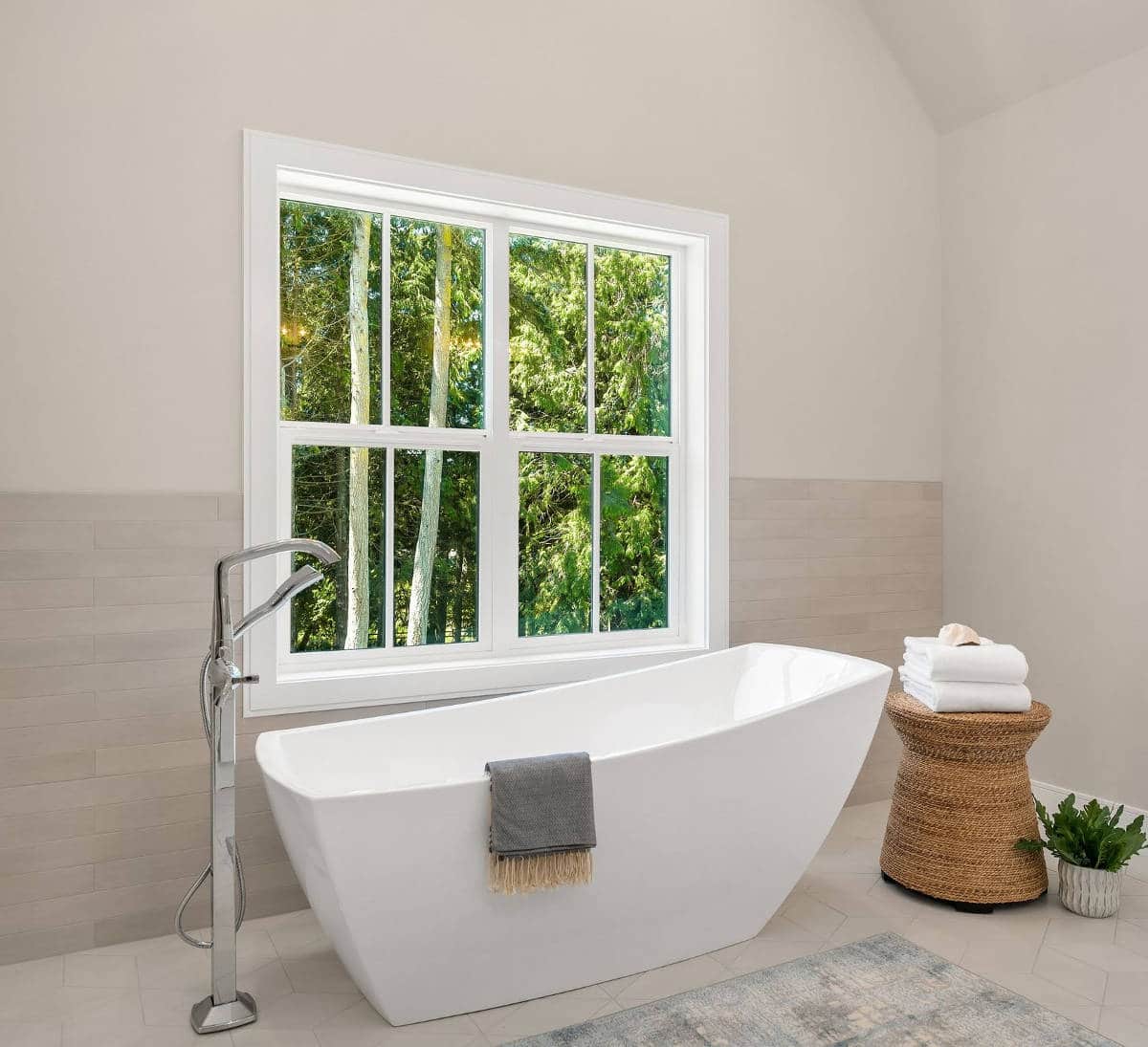 A bathroom with a tub and a window with trees in the background