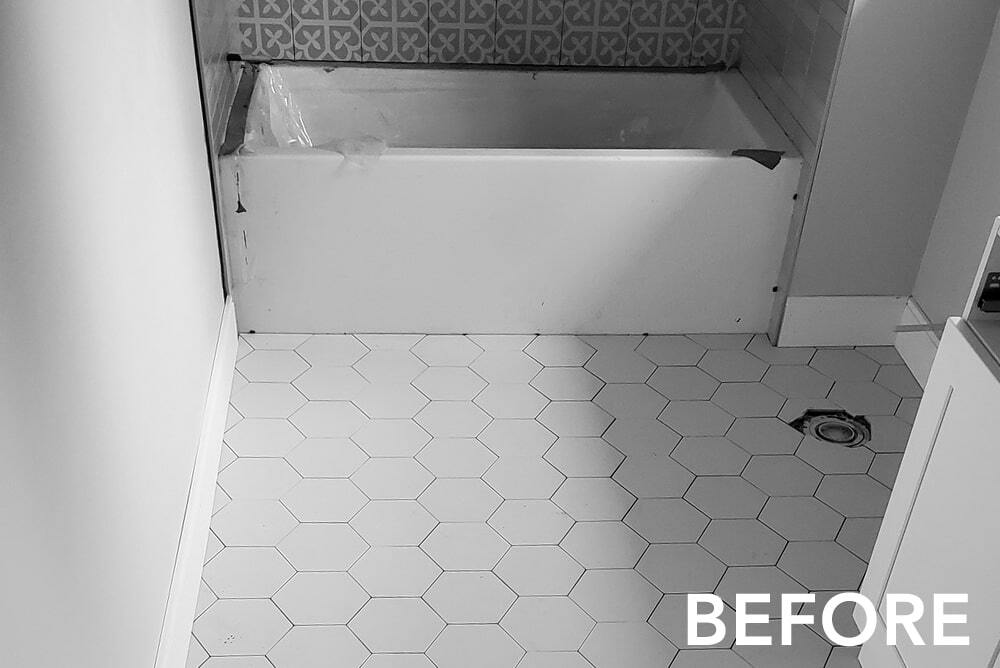 A black and white photo of a bathroom with a bathtub and tile floor.