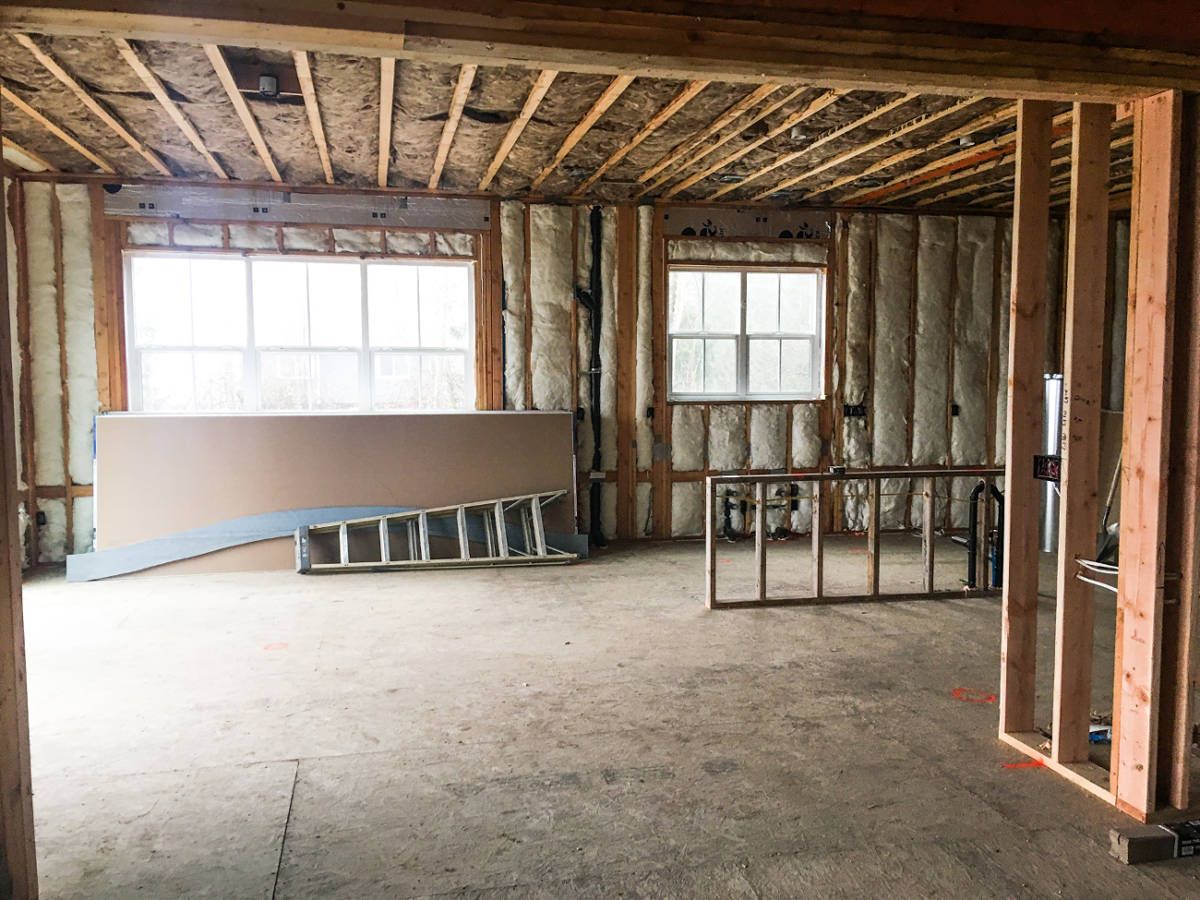 A room in a house under construction with a ladder and a window.