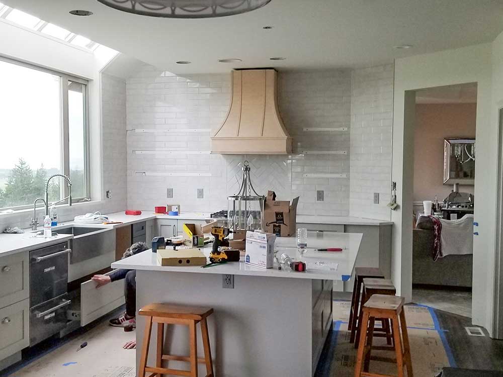 A kitchen under construction with a large island and stools.