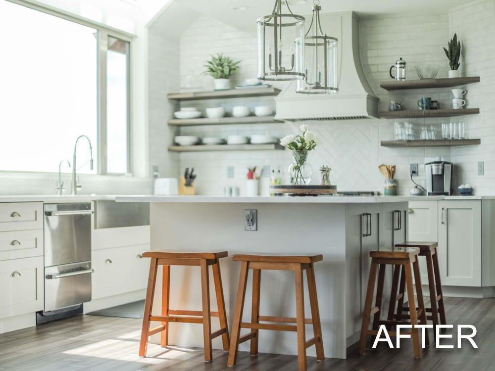 A kitchen with white cabinets , stainless steel appliances , and wooden stools.