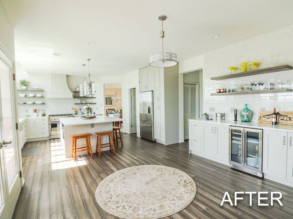 A kitchen with white cabinets , stainless steel appliances , wooden floors and a rug.