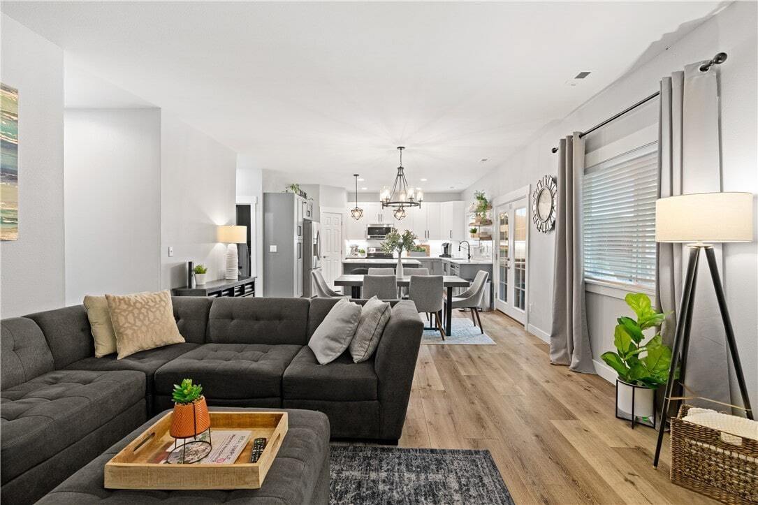 A living room with a sectional couch , ottoman , coffee table , and lamp.