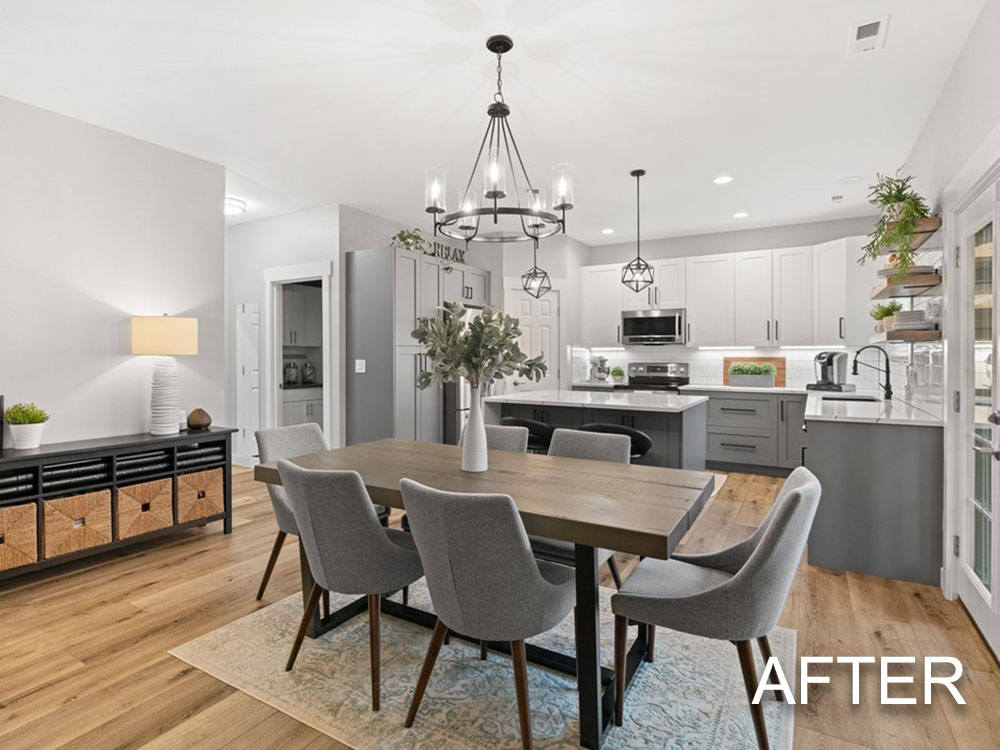 A dining room with a table and chairs and a kitchen in the background.