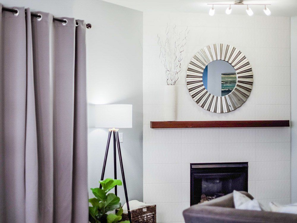 A living room with a fireplace , couch , lamp and mirror.