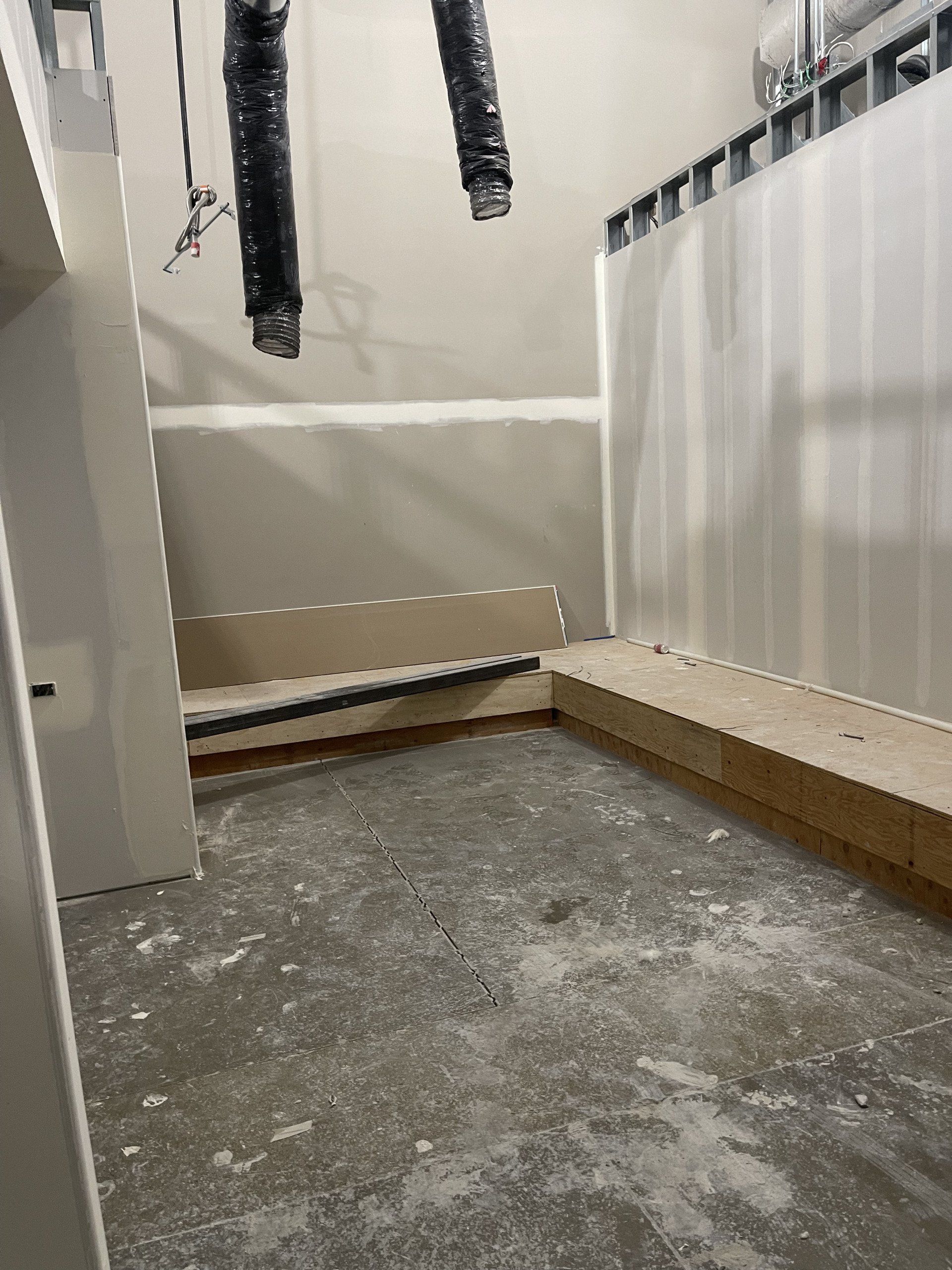 A room with a concrete floor and a white wall.