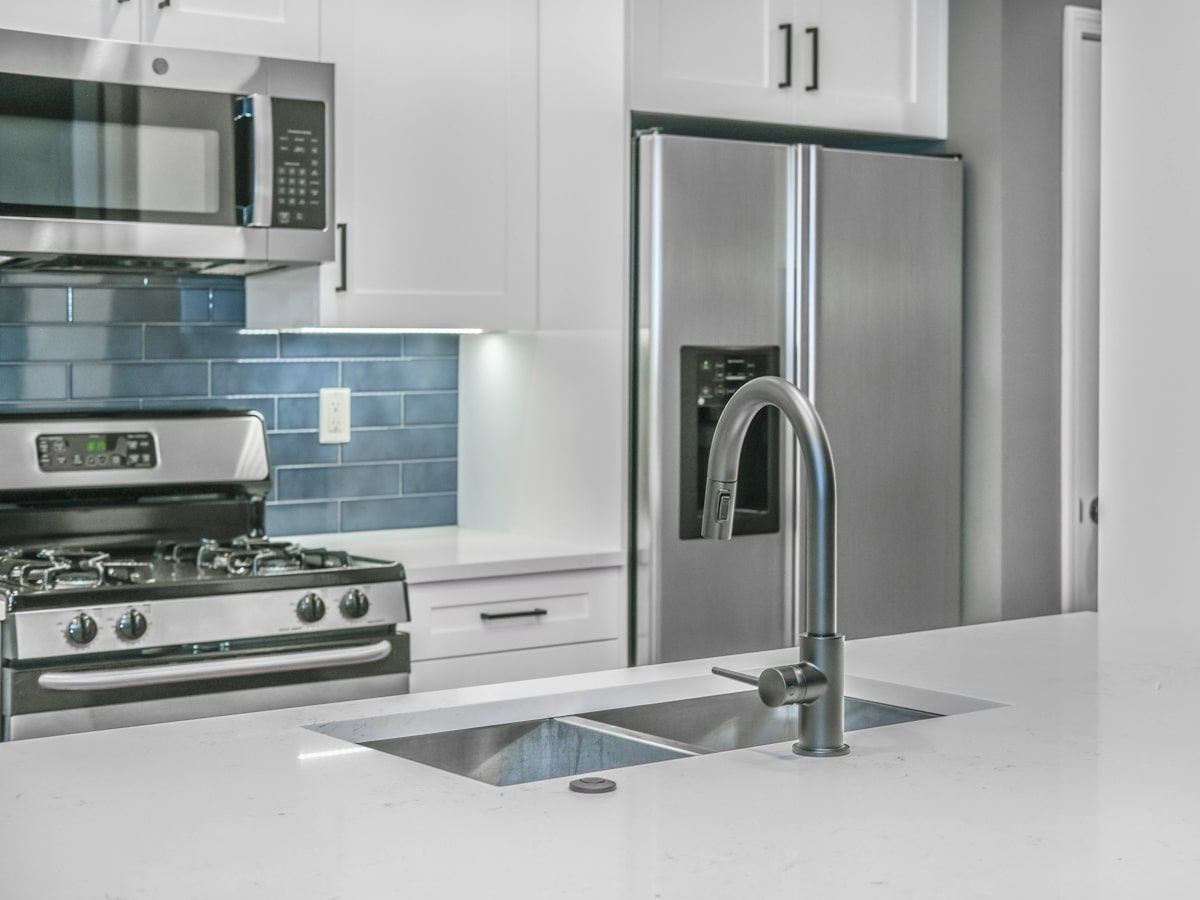 A kitchen with a stove , refrigerator , sink and microwave.