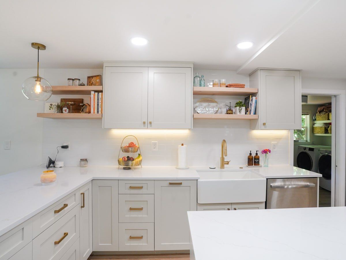 A kitchen with white cabinets , a sink , and a dishwasher.