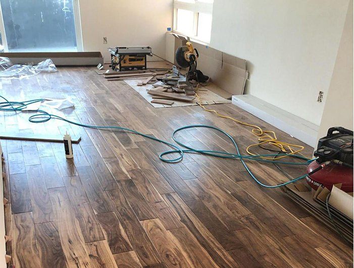 A wooden floor is being installed in a living room.